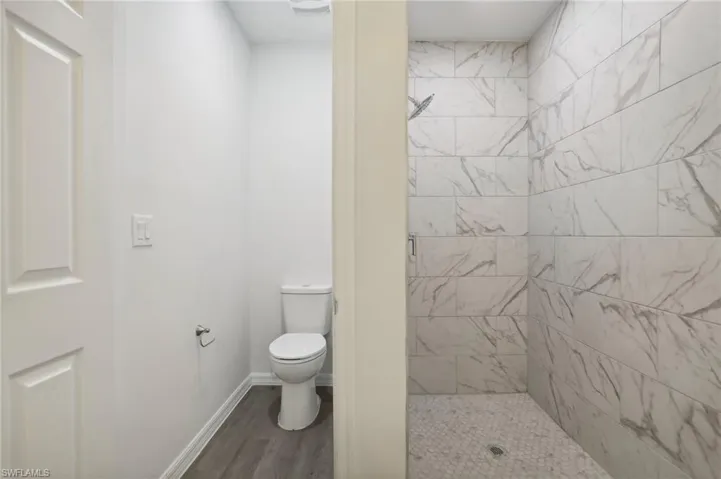 Bathroom featuring a tile shower, hardwood / wood-style floors, and toilet