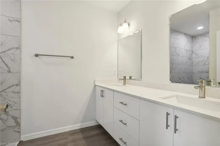 Bathroom featuring a tile shower, vanity, and hardwood / wood-style floors