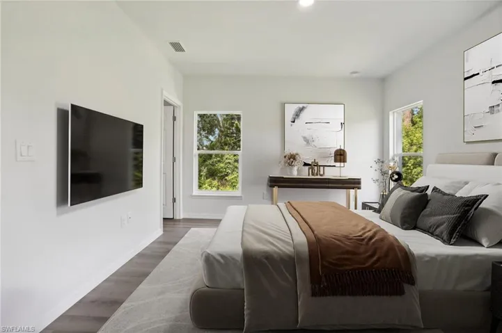 Bedroom featuring multiple windows and dark hardwood / wood-style floors