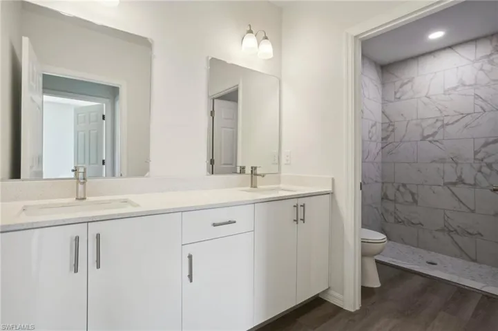 Bathroom featuring hardwood / wood-style flooring, toilet, a tile shower, and vanity