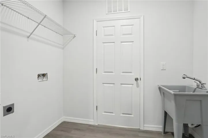 Clothes washing area featuring sink, electric dryer hookup, and wood-type flooring