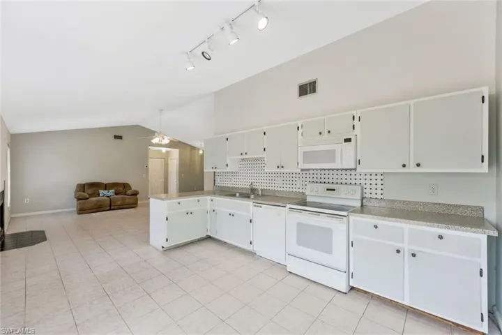 Kitchen featuring white cabinets, white appliances, sink, ceiling fan, and tasteful backsplash