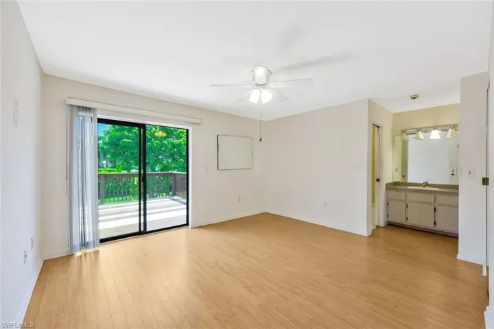 Unfurnished bedroom featuring ensuite bath, light wood-type flooring, sink, access to outside, and ceiling fan