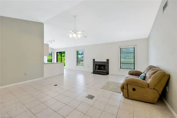 Living room featuring vaulted ceiling, light tile patterned floors, ceiling fan, and a tile fireplace