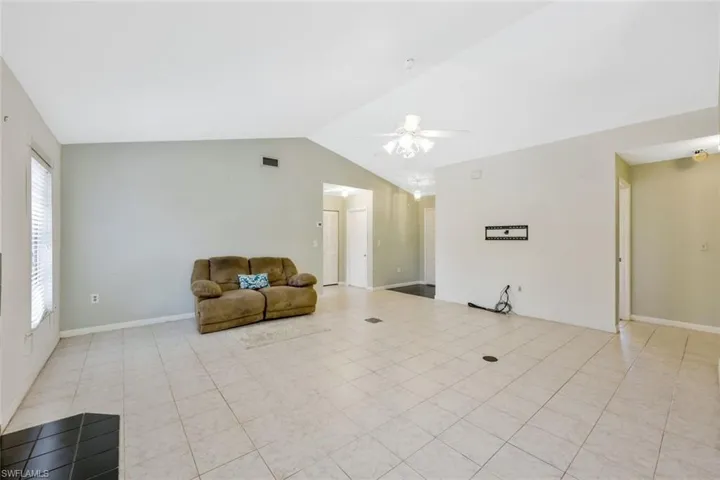 Unfurnished living room with lofted ceiling, ceiling fan, and light tile patterned flooring