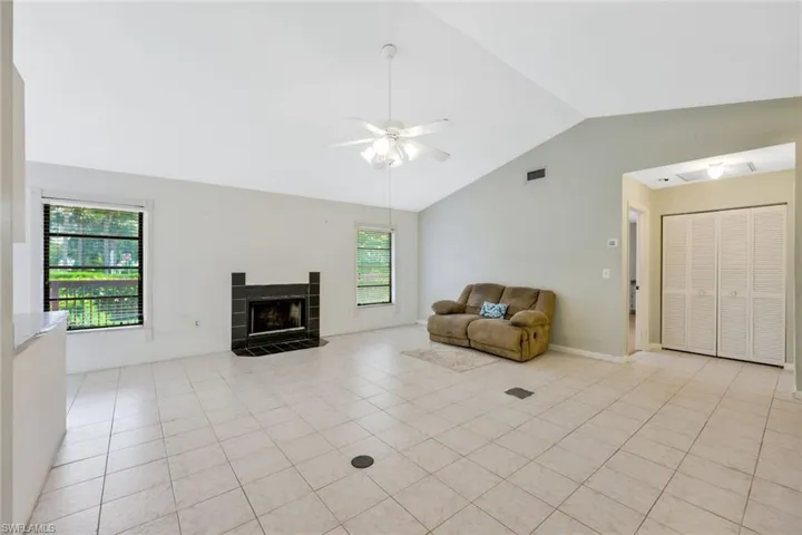 Unfurnished living room featuring high vaulted ceiling, ceiling fan, a fireplace, and light tile patterned flooring