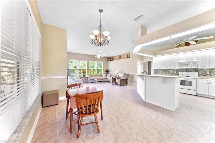 Tiled dining room featuring sink and ceiling fan with notable chandelier