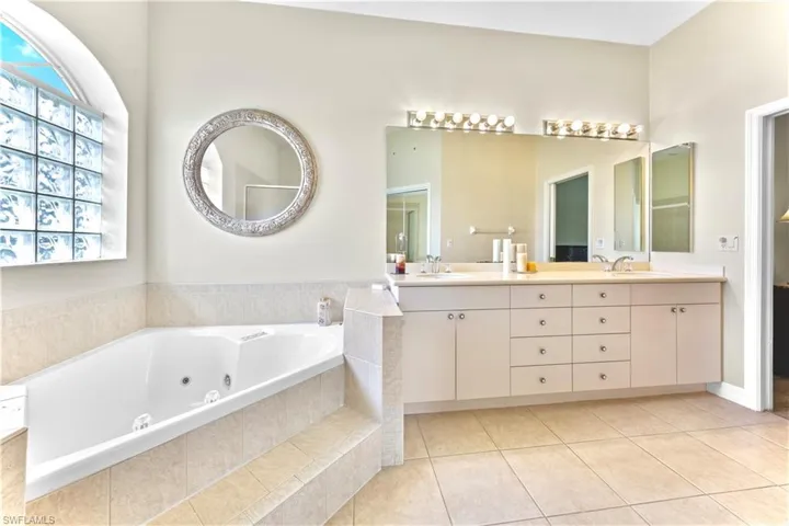 Bathroom with tile patterned flooring, vanity, and a relaxing tiled tub