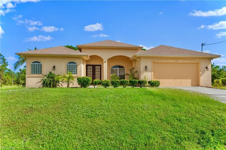 View of front of house with a front lawn, a garage, and french doors