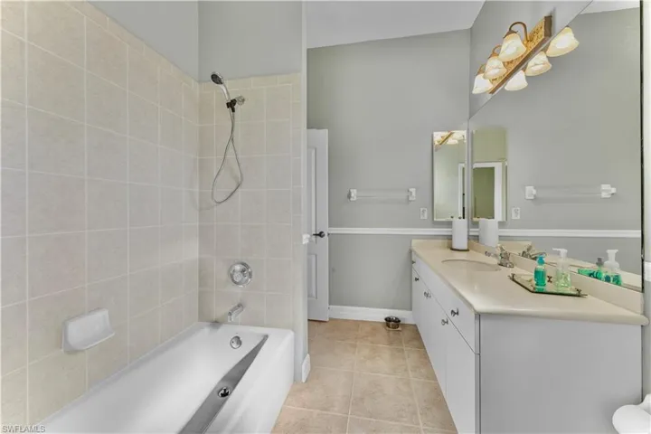 Bathroom with tile patterned flooring, vanity, and tiled shower / bath combo