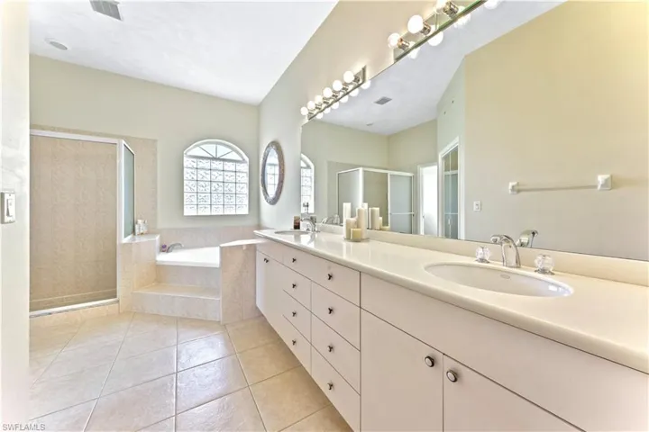 Bathroom featuring tile patterned flooring, shower with separate bathtub, and vanity