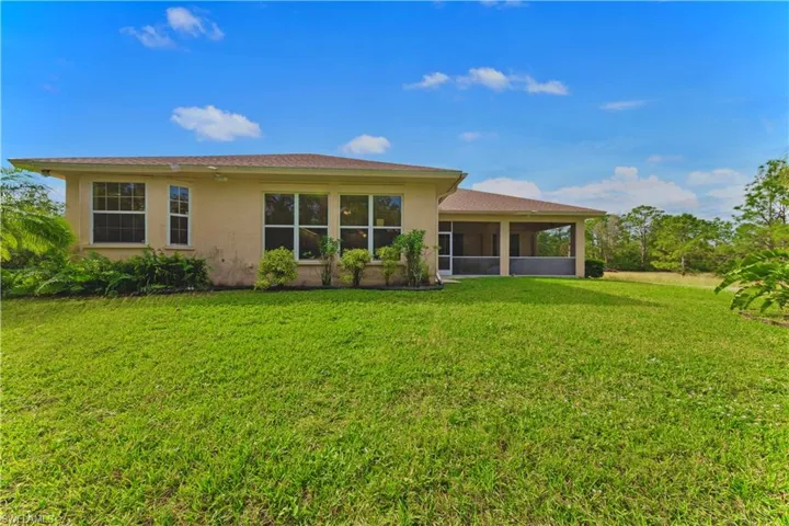 Back of property with a lawn and a sunroom
