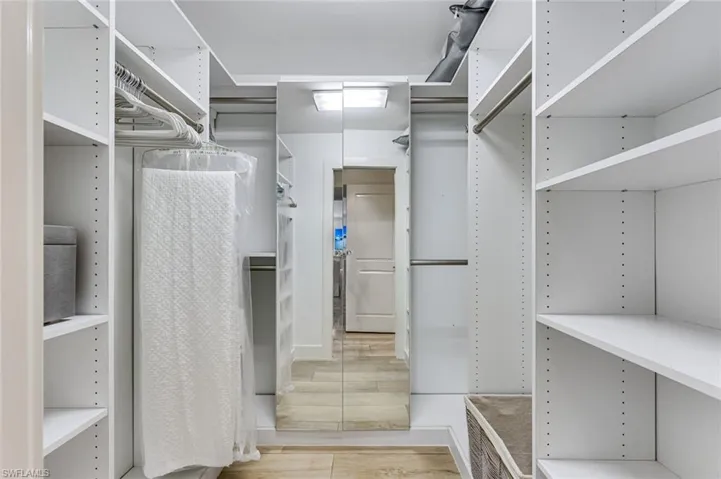 Primary walk in closet with custom cabinetry