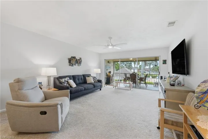 Carpeted living area with white walls and a ceiling fan