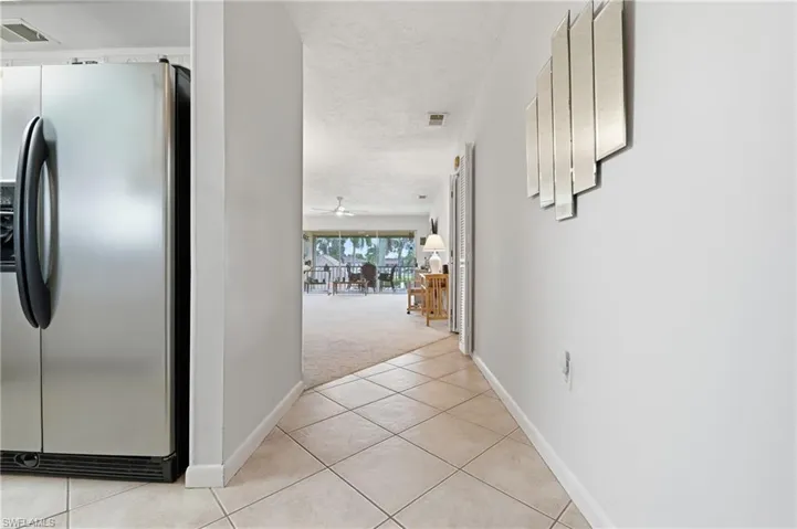 Stainless steel refrigerator, diagonal tile flooring, textured ceiling, and carpeted area