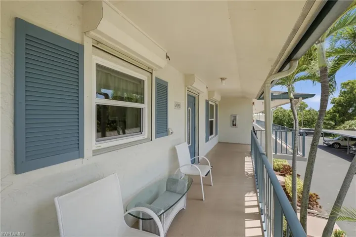 Covered entry porch featuring blue louvered shutters, hurricane shutter, and a blue entry door