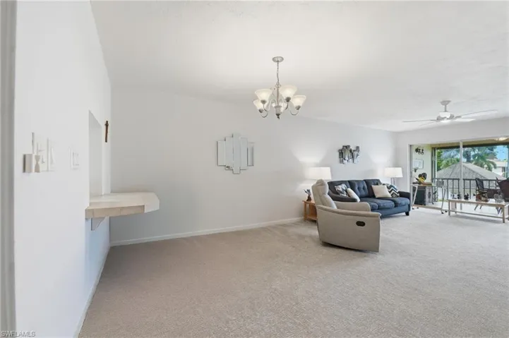 Spacious living area featuring neutral carpeting, a built-in stone-finish countertop, and a ceiling fan
