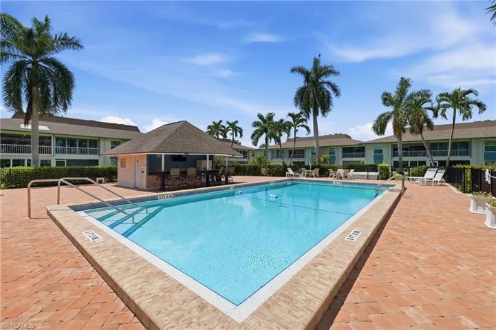 Community swimming pool with integrated steps, surrounded by brick paver decking