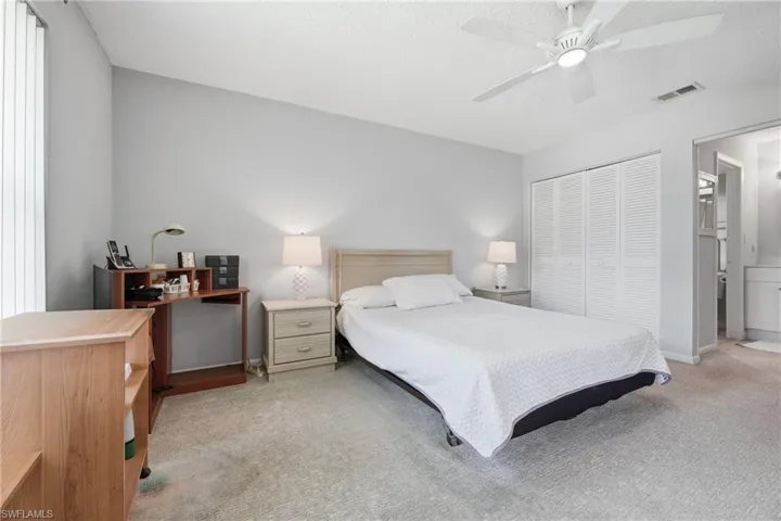 Light gray wall paint, textured ceiling, ceiling fan with integrated lighting, bi-fold louvered closet doors, and light gray carpeting