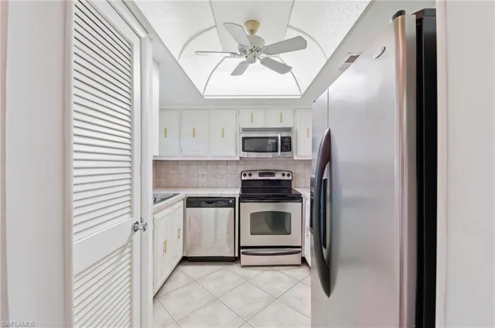 Kitchen featuring stainless steel appliances, white cabinetry, tile flooring, and a ceiling fan