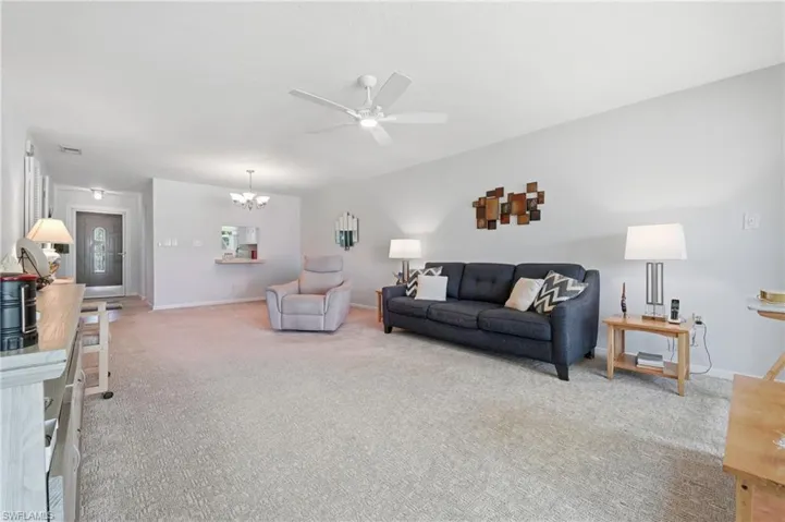 Open-concept living area with light-toned carpet flooring and a ceiling fan