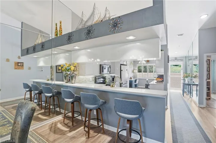 Kitchen with a breakfast bar area, stainless steel appliances, light wood-style flooring, light countertops, and recessed lighting