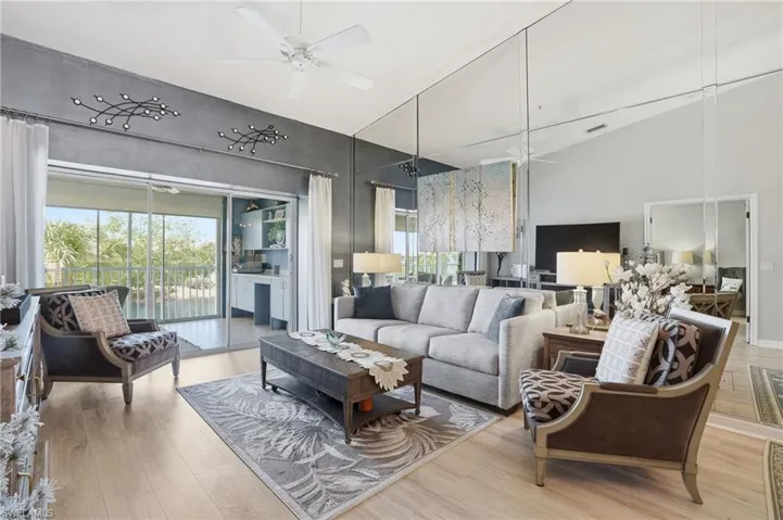 Living area featuring ceiling fan, light wood finished floors, and lofted ceiling