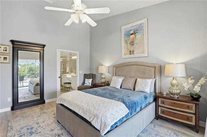 Bedroom featuring light wood finished floors, connected bathroom, a ceiling fan, and a high ceiling
