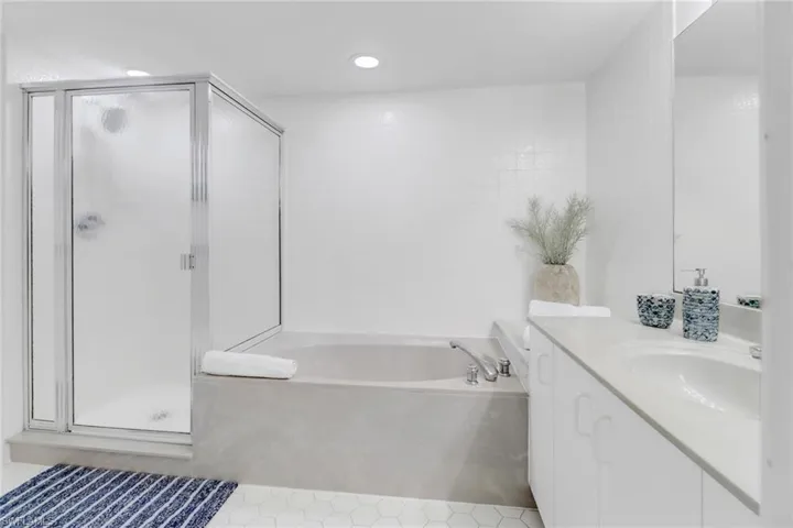 Full bathroom featuring vanity, a shower stall, a bath, and recessed lighting