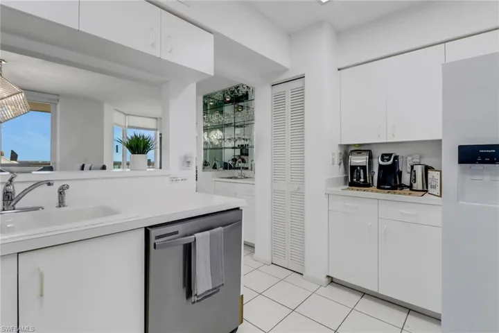 Kitchen with white cabinetry, dishwasher, light countertops, white refrigerator with ice dispenser, and light tile patterned flooring
