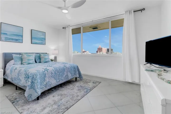 Bedroom with a ceiling fan, multiple windows, and light tile patterned floors
