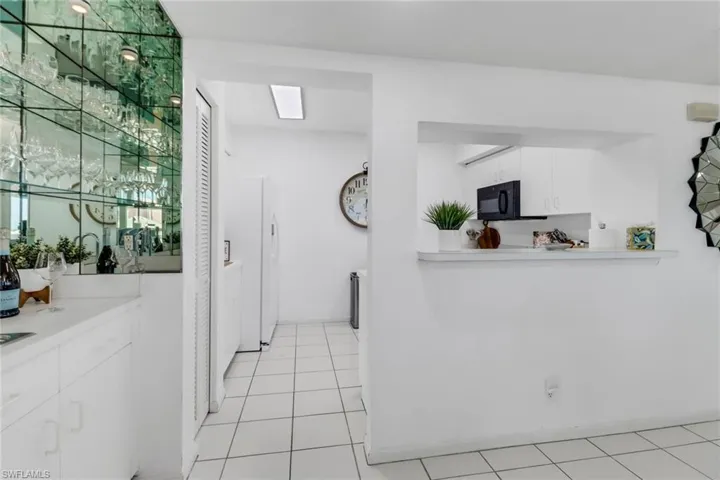 Kitchen with white cabinets, light countertops, freestanding refrigerator, and light tile patterned flooring