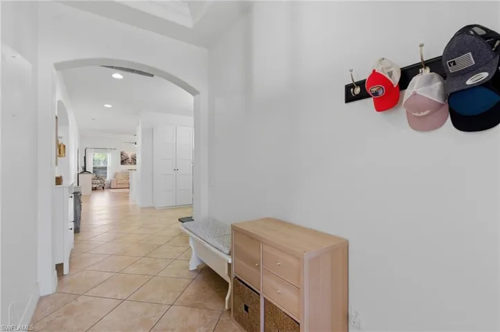 Hallway with arched walkways, light tile patterned flooring, and recessed lighting