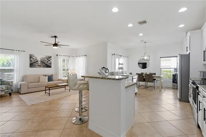 Kitchen featuring a kitchen breakfast bar, white cabinetry, light stone countertops, and light tile patterned flooring