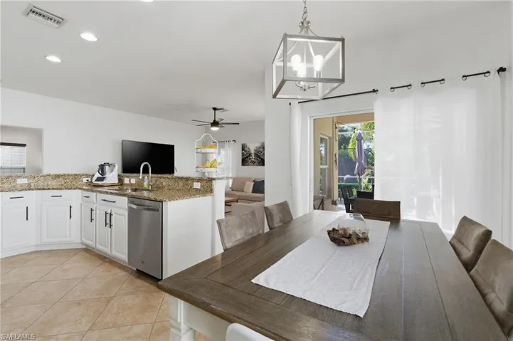 Dining room featuring a ceiling fan, suspended lighting, and light tile patterned flooring
