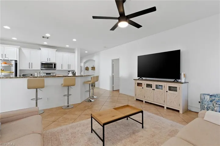 Living room featuring a ceiling fan, arched walkways, recessed lighting, and light tile patterned floors