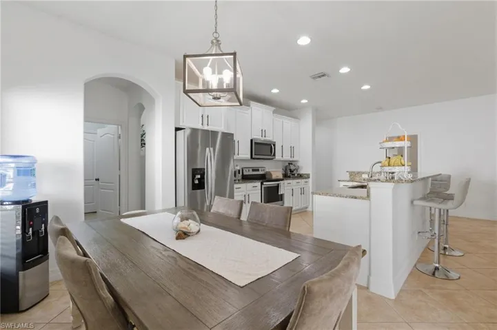 Dining room featuring arched walkways, light tile patterned floors, and suspended lighting