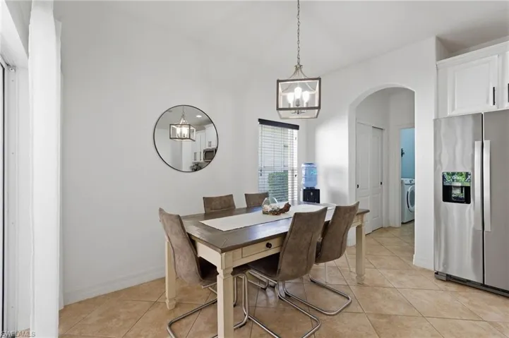 Dining room with arched walkways, hanging lights, light tile patterned flooring, and washer / clothes dryer