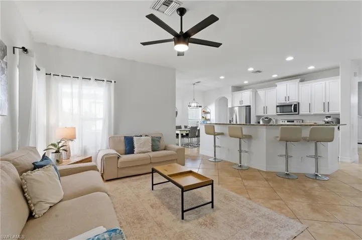 Living room featuring a ceiling fan, recessed lighting, arched walkways, and light tile patterned flooring