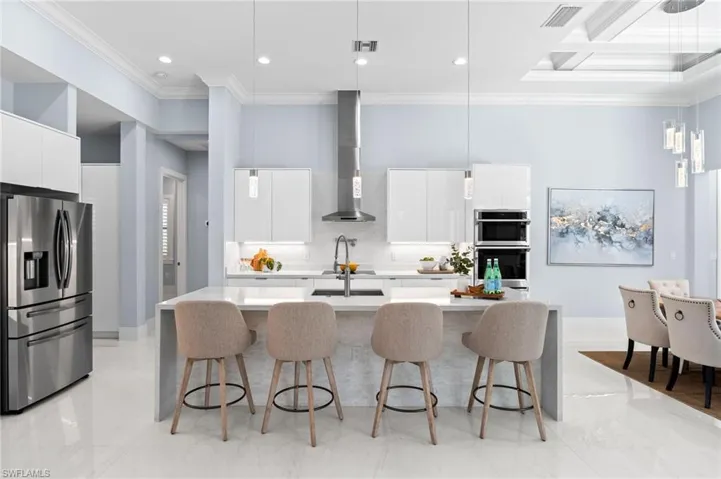 Stunning Chef's kitchen -appointed with waterfall quartz countertops, sleek white gloss cabinetry, a breakfast bar, and an inviting eat-in area—perfect for entertaining.
