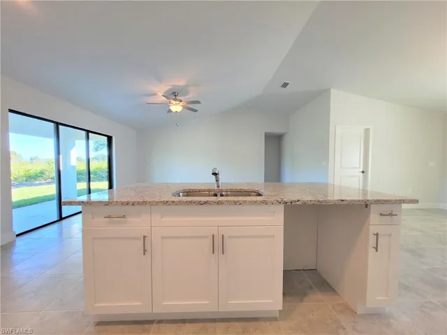 Kitchen with light tile floors, sink, and a center island with sink