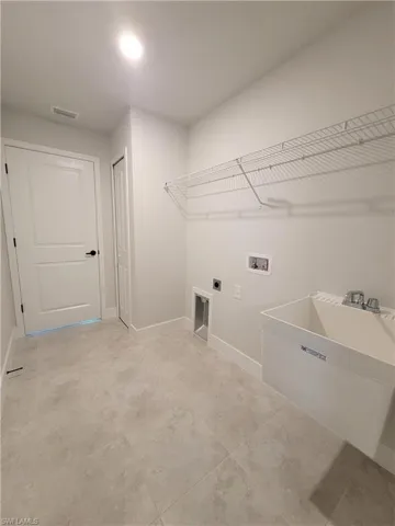 Laundry area with electric dryer hookup, sink, light tile flooring, and hookup for a washing machine