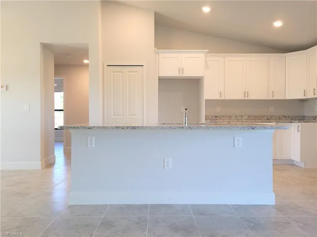 Kitchen with a center island, white cabinets, and vaulted ceiling