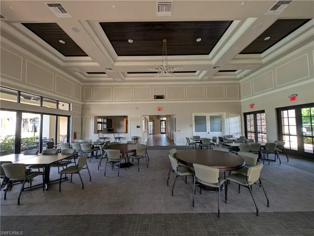 Dining room with dark carpet, coffered ceiling, ornamental molding, french doors, and a chandelier