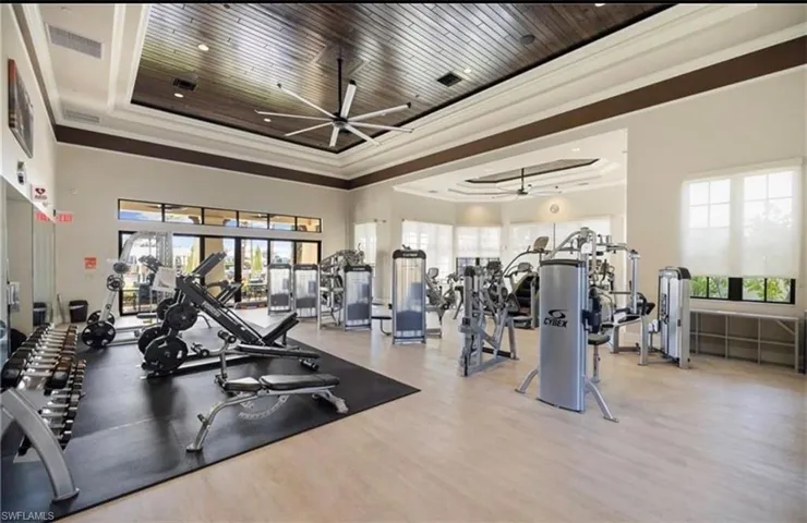 Exercise room with a ceiling fan, crown molding, and a high tray ceiling