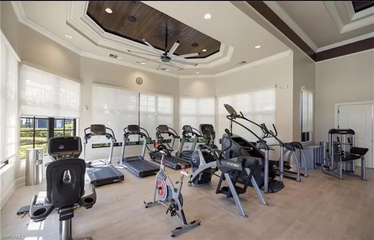 Workout area featuring ceiling fan, recessed lighting, a raised ceiling, and crown molding