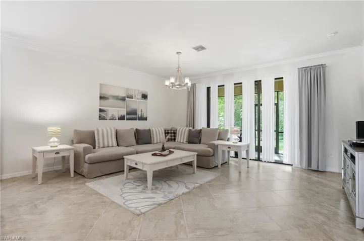 Living area featuring crown molding and suspended lighting