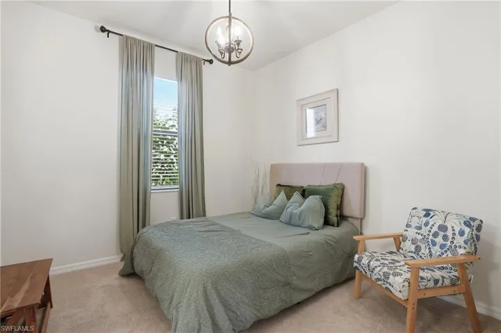 Bedroom featuring a chandelier and light carpet
