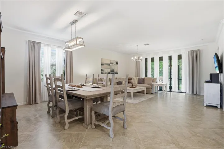 Dining room with crown molding, healthy amount of natural light, and suspended lighting