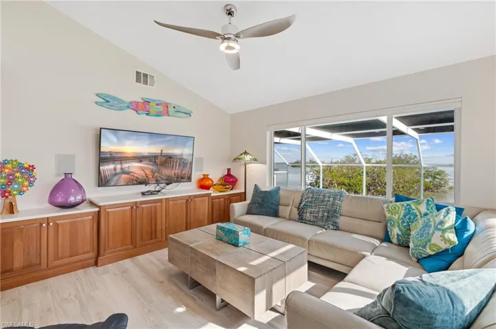 Living room with lofted ceiling, ceiling fan, and light hardwood / wood-style flooring / virtually enhanced